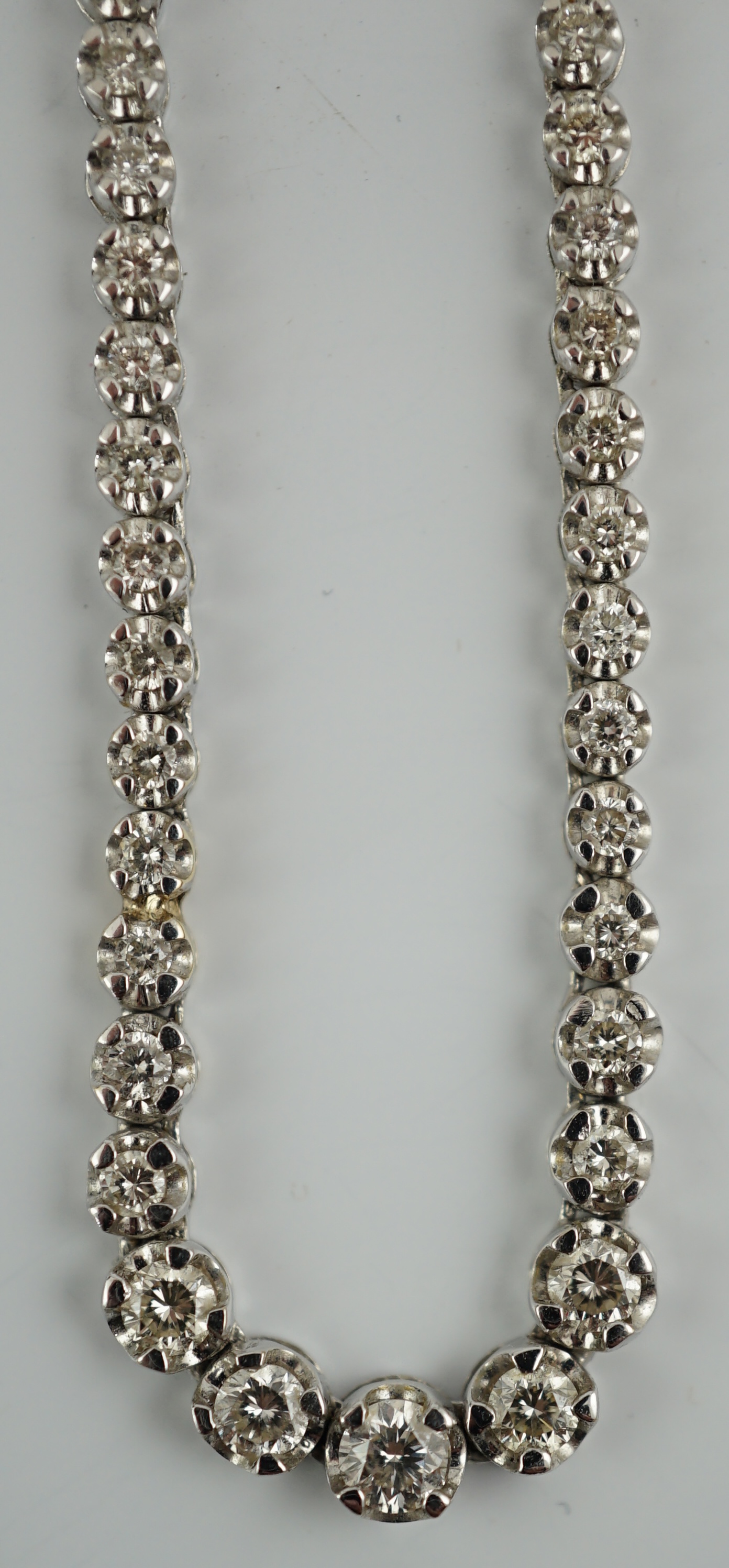 A modern 18k gold and illusion set diamond line necklace, set with diamond chips and five graduated larger stones, 40cm, gross weight 17 grams. Condition - poor to fair (old repair to one link)